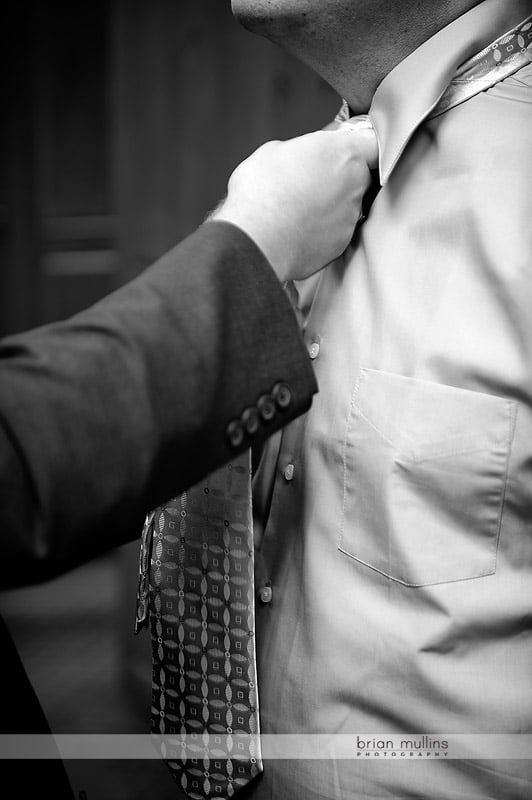 best man helping groom put on tie