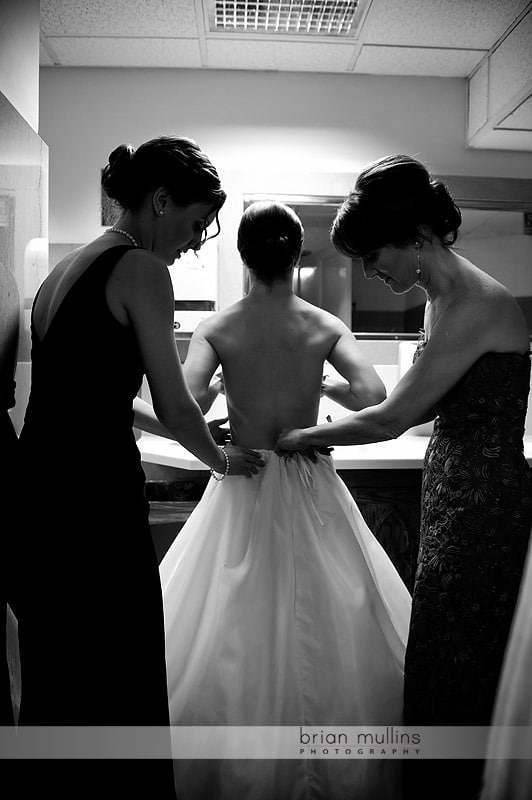 bride putting on wedding gown