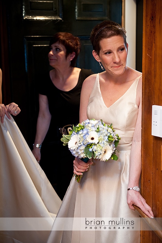 bride peeking around the corner at her wedding party